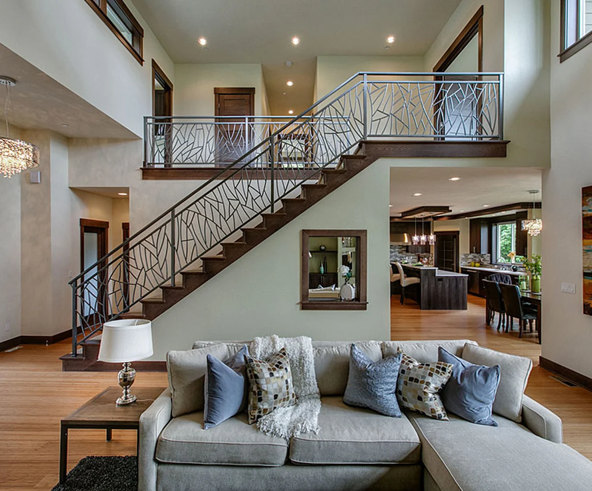 A modern living room with a stylish metal staircase railing, featuring a cozy sofa and a seamless open floor plan.