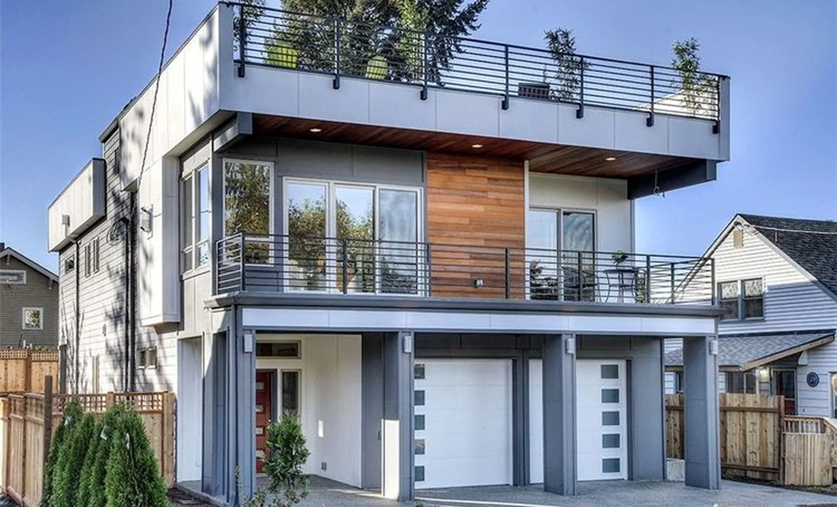 A modern house with a sleek rooftop terrace, stylish garage doors, and a mix of metal and wood accents.