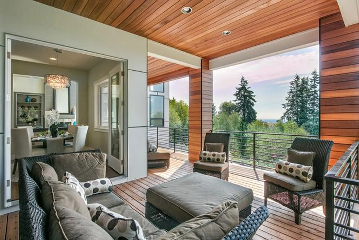 An outdoor balcony with wicker seating and a stunning view of trees and the horizon.
